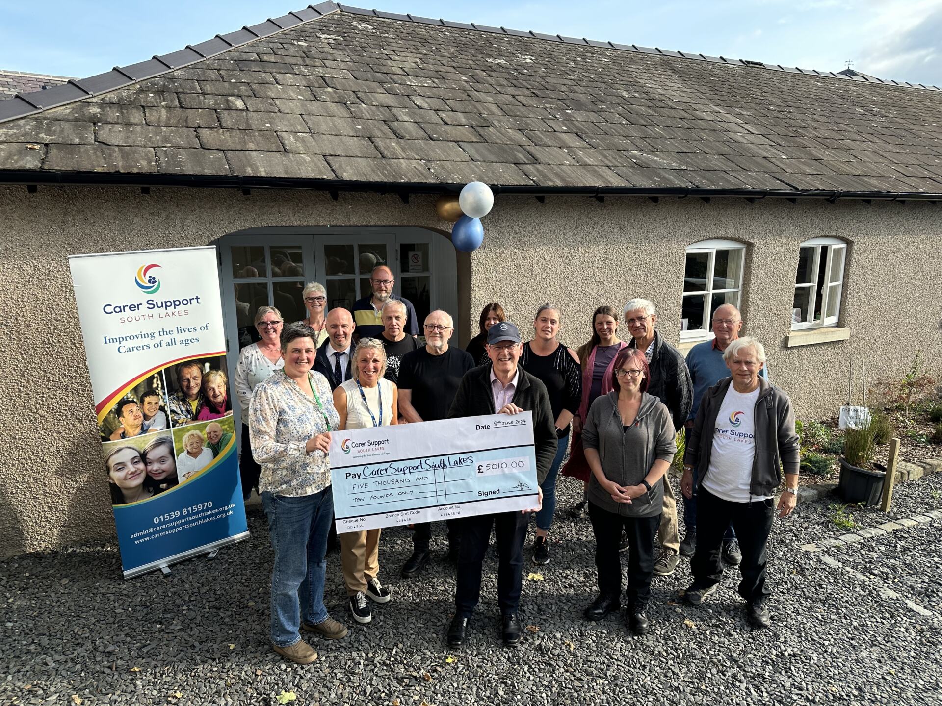 Stuart Graves, co-organiser of the K2K walk and Volunteers who took part, hands over the cheque for £5,010.00 to Carer Support South Lakes.