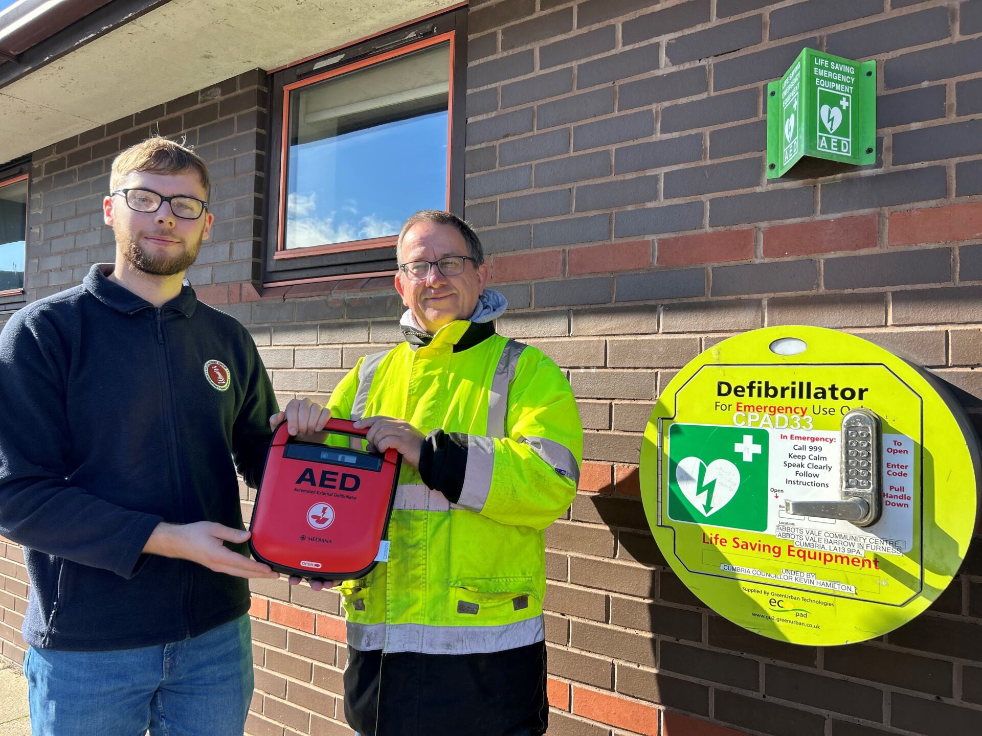 Cameron Bell from JF Hornby & Co hands the defib to Cllr Andy Coles.